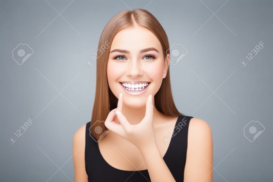 Junge lächelnde Frau mit Invisalign-Klammern im Studio, Zahnpflege und kieferorthopädisches Konzept