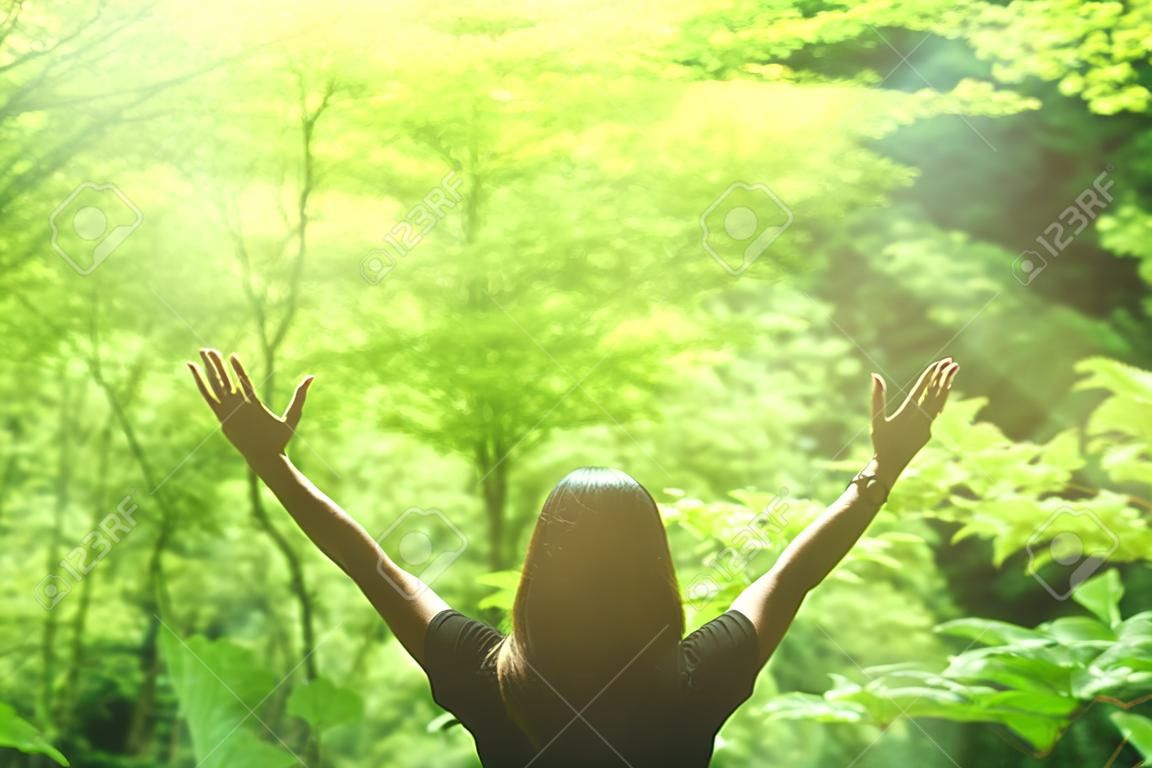 Liberdade sentir-se bem e viajar conceito de aventura. Copiar espaço silhueta mulher levantando mãos na natureza folha verde fundo na floresta. Tom vintage filtro efeito estilo de cor.