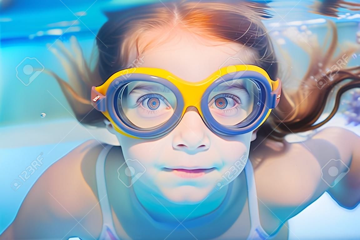 los niños bajo el agua chica con gafas de natación y un gesto gracioso