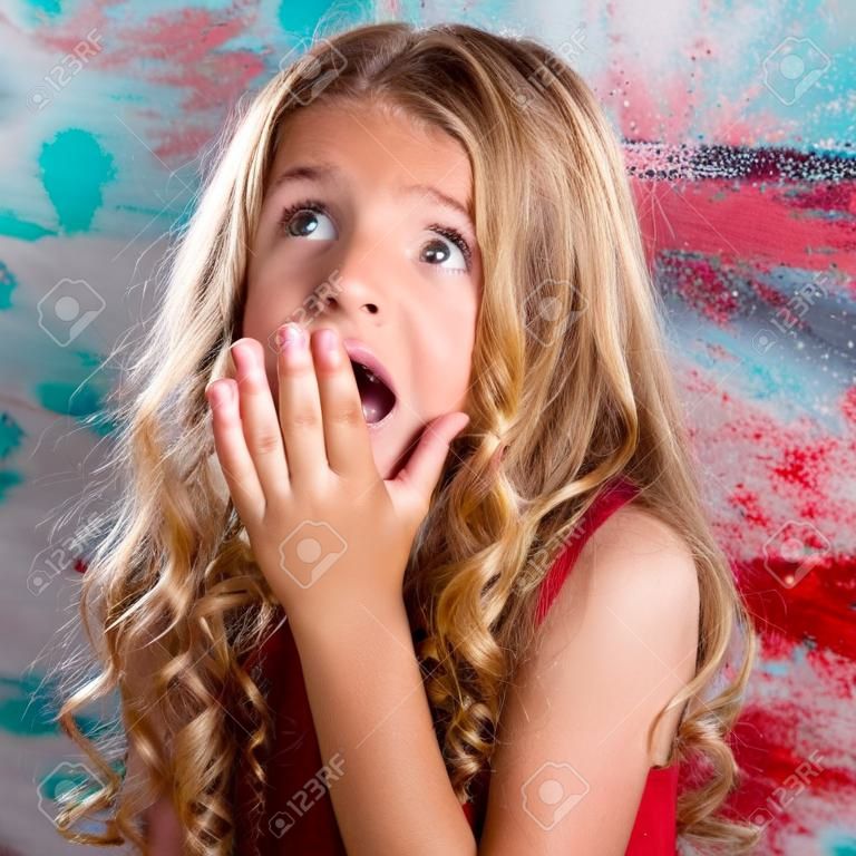 Enfant fille blonde surpris mains d'expression dans le geste du visage