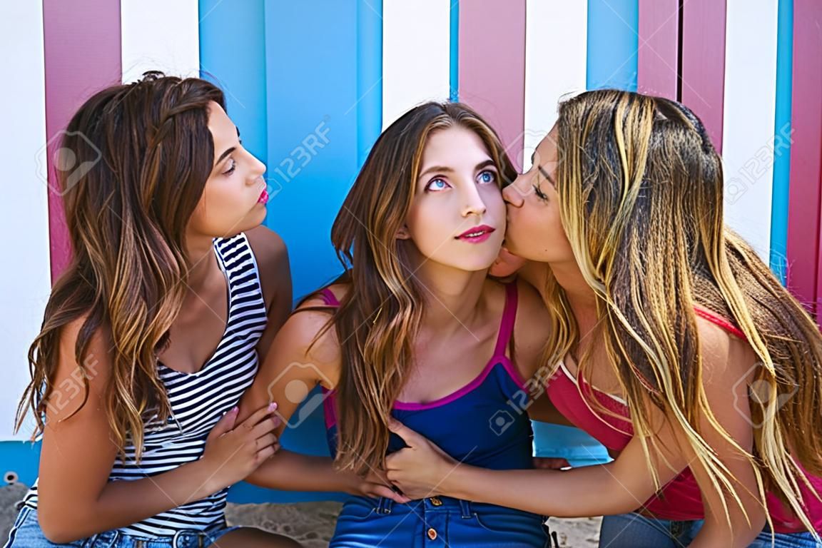 Three teen best friends girls kissing in a beach stripes background