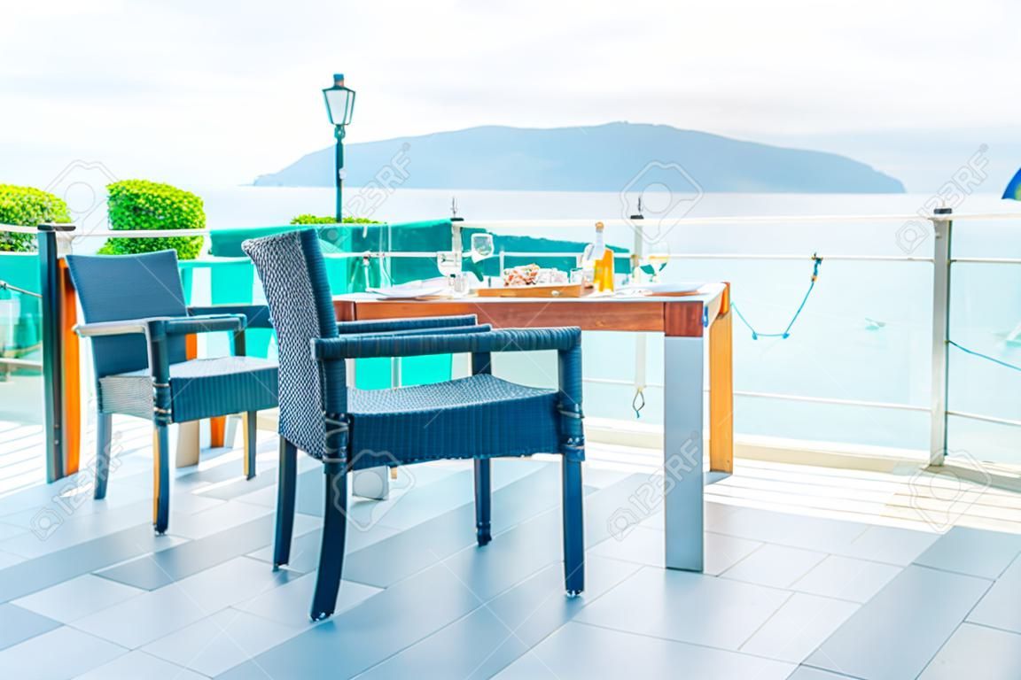 cadeira de pátio vazio e mesa com fundo de vista para o mar
