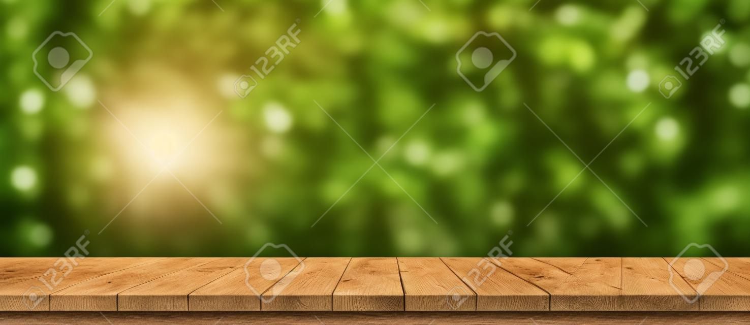 Empty wood table and defocused bokeh and blur background of garden trees with sunlight. product display template.