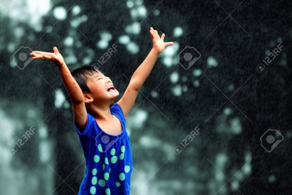 As crianças asiáticas brincam alegremente na chuva.