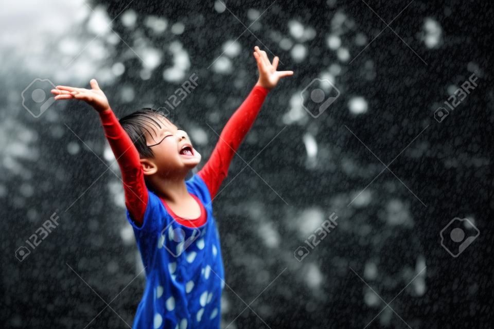 As crianças asiáticas brincam alegremente na chuva.