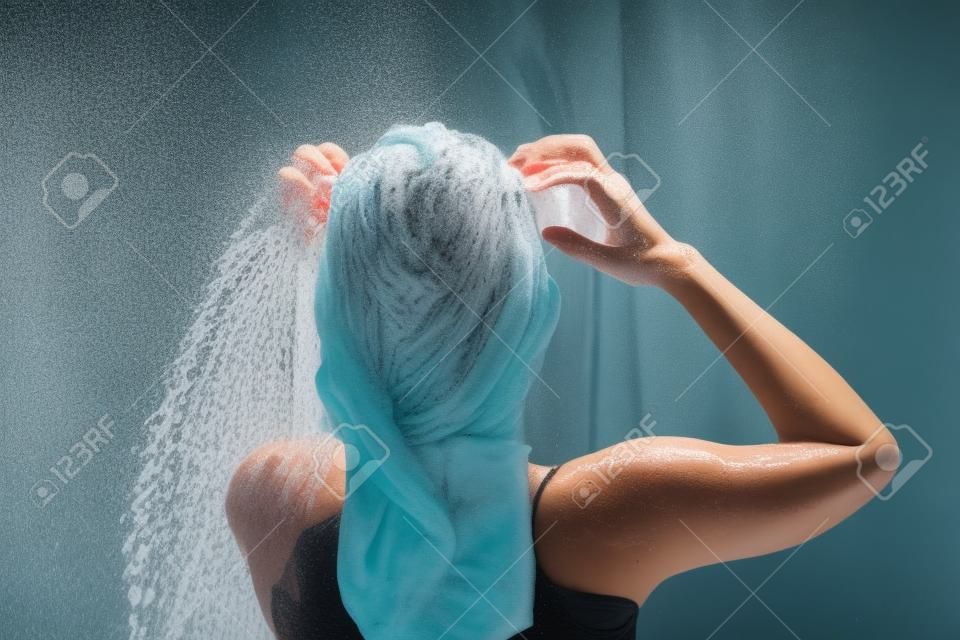 Mujer bañándose y lavándose el pelo relajada.