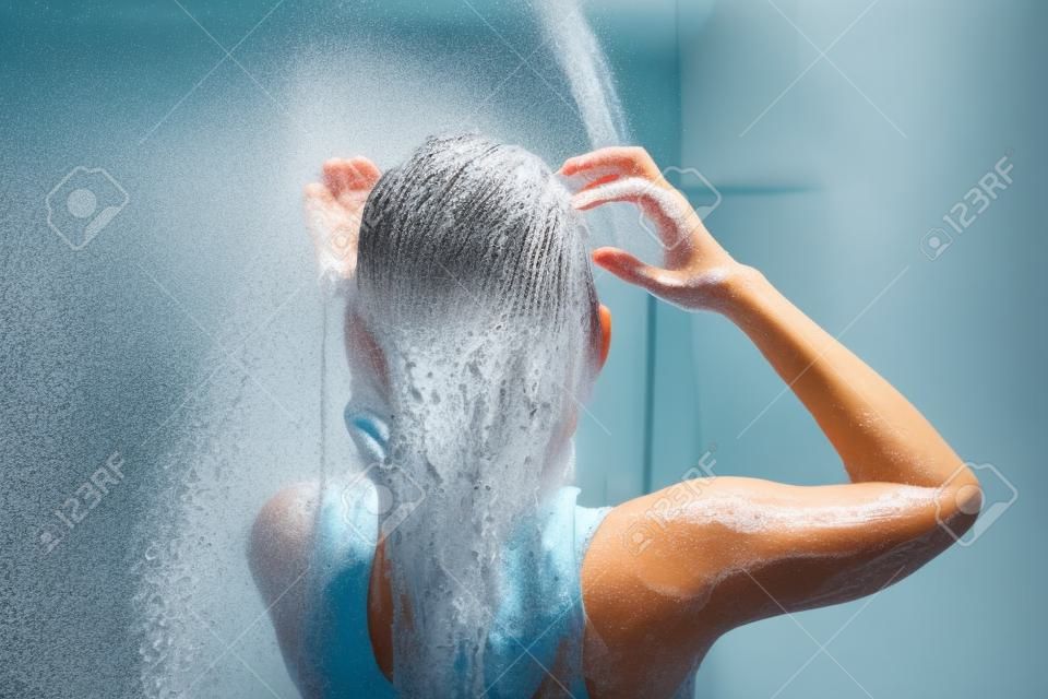 Donna che si bagna e si lava i capelli rilassata.