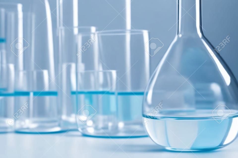Lab glassware containing chemical liquid with laboratory background, science research and development concept