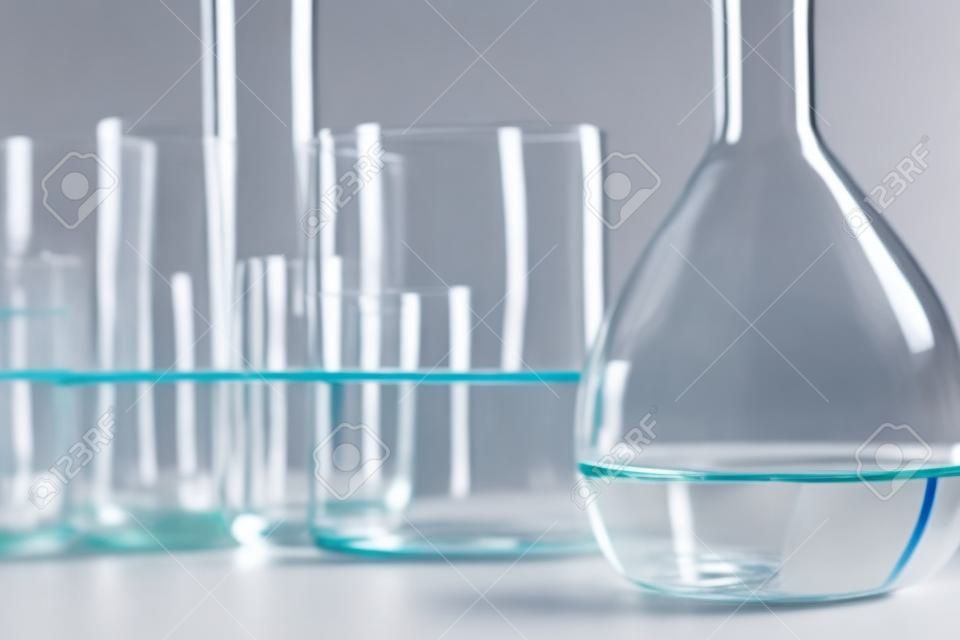 Lab glassware containing chemical liquid with laboratory background, science research and development concept