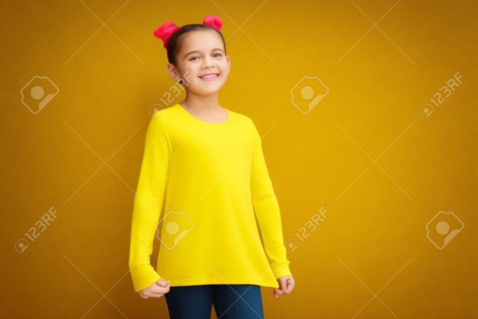 Feliz niña bonita en camiseta amarilla con caramelos de colores