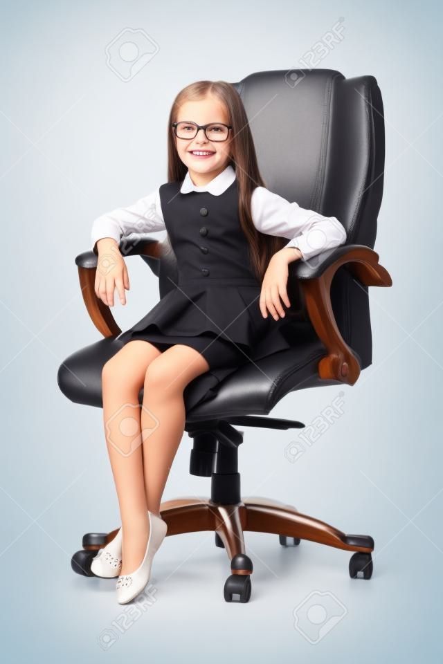 Adorable niña sonriente linda que se sienta en la silla en la oficina vestida como una empresaria en el fondo blanco morena caucásica hermoso atractivo feliz exitoso confiado aislado administrar.