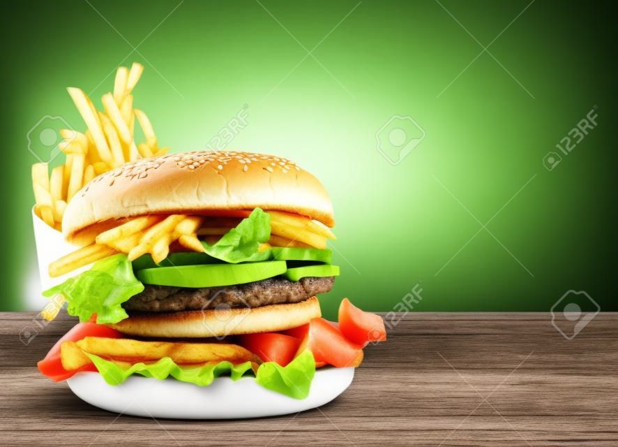 Fresh double hamburger and french fries on green nature background. Copy space