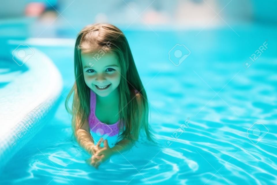 Entzückendes Mädchen im Schwimmbad sieht in die Kamera
