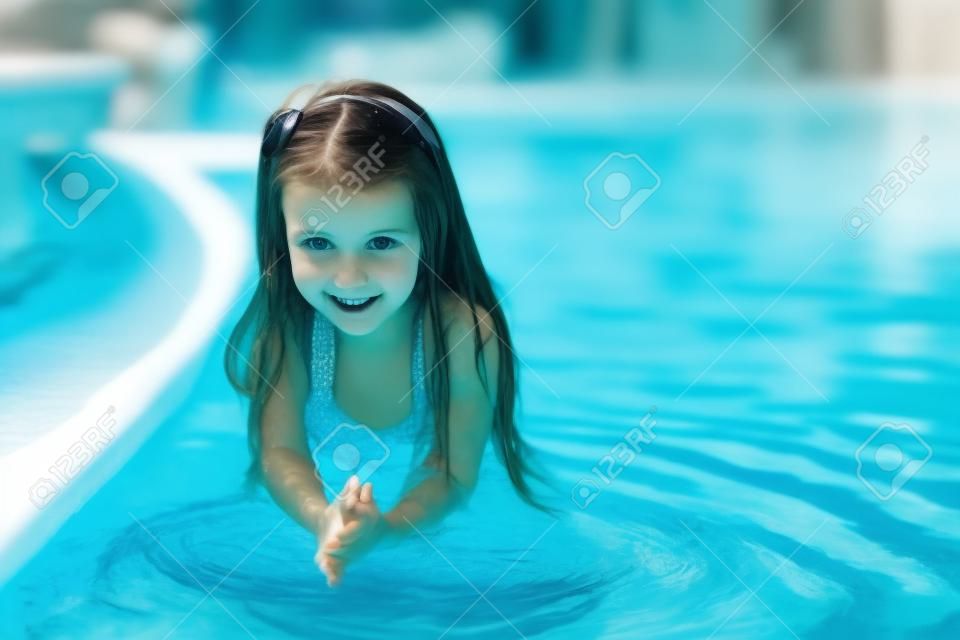 Adorable petite fille dans la piscine regarde la caméra