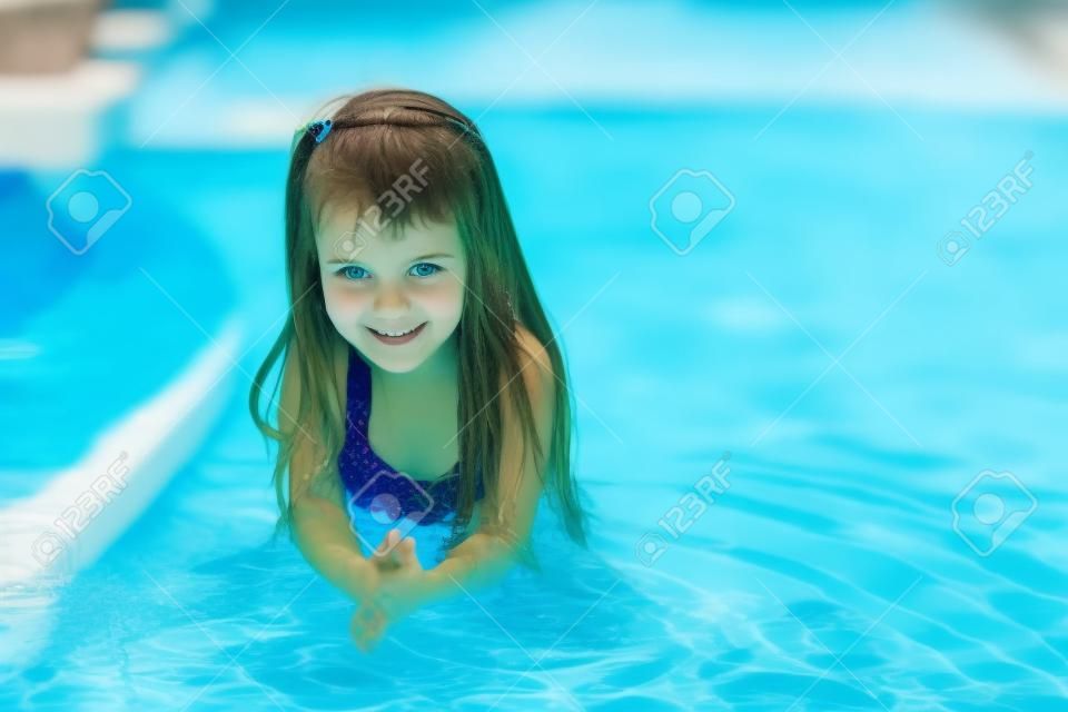 Adorable girl in the swimming pool looks at camera
