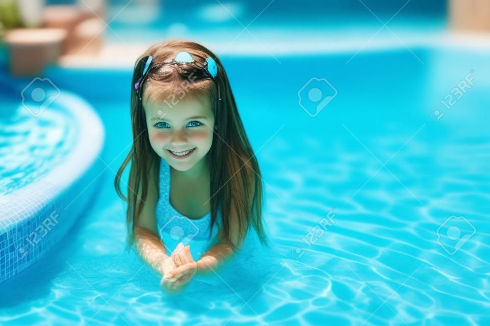 Adorable petite fille dans la piscine regarde la caméra
