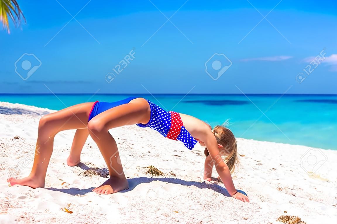 Adorable little sporty girl on white tropical beach
