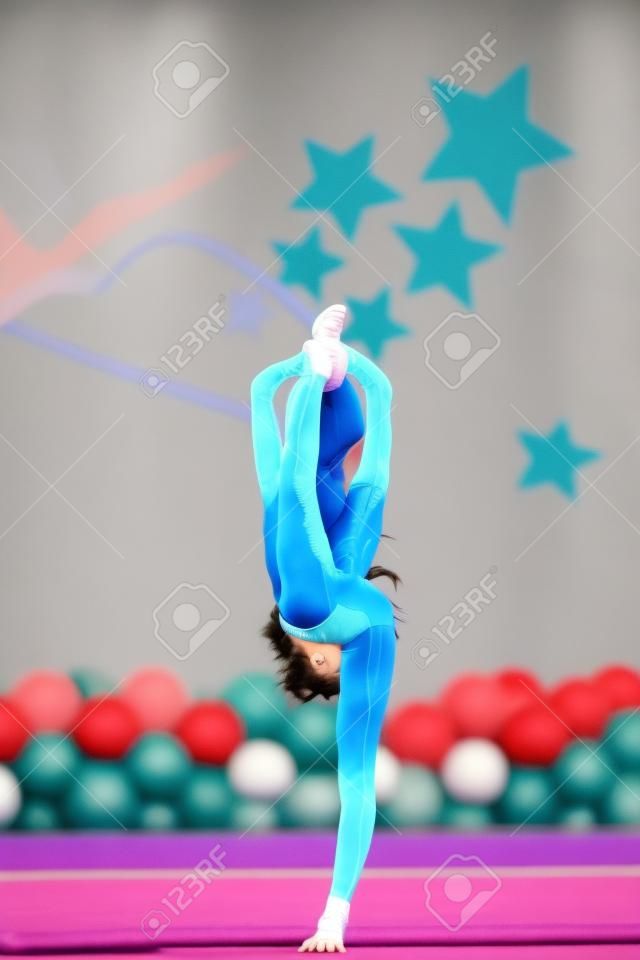 Little beautiful gymnast on carpet. Adorable gymnast participates in competitions in rhythmic gymnastics