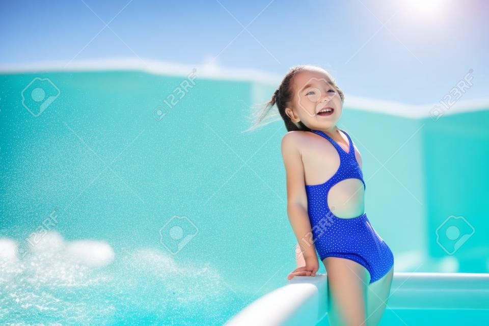Little active adorable girl in outdoor swimming pool ready to swim