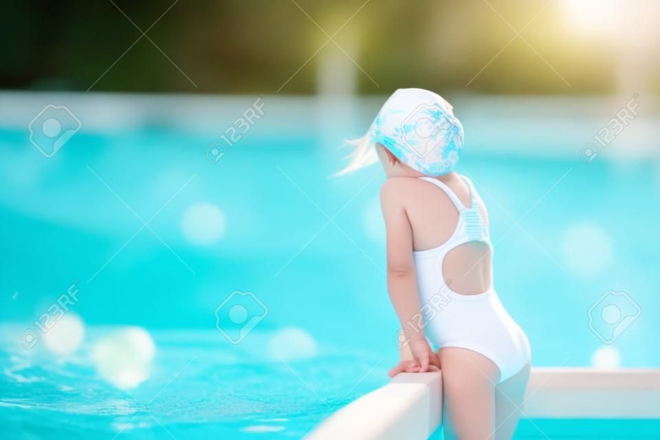 Little active adorable girl in outdoor swimming pool ready to swim