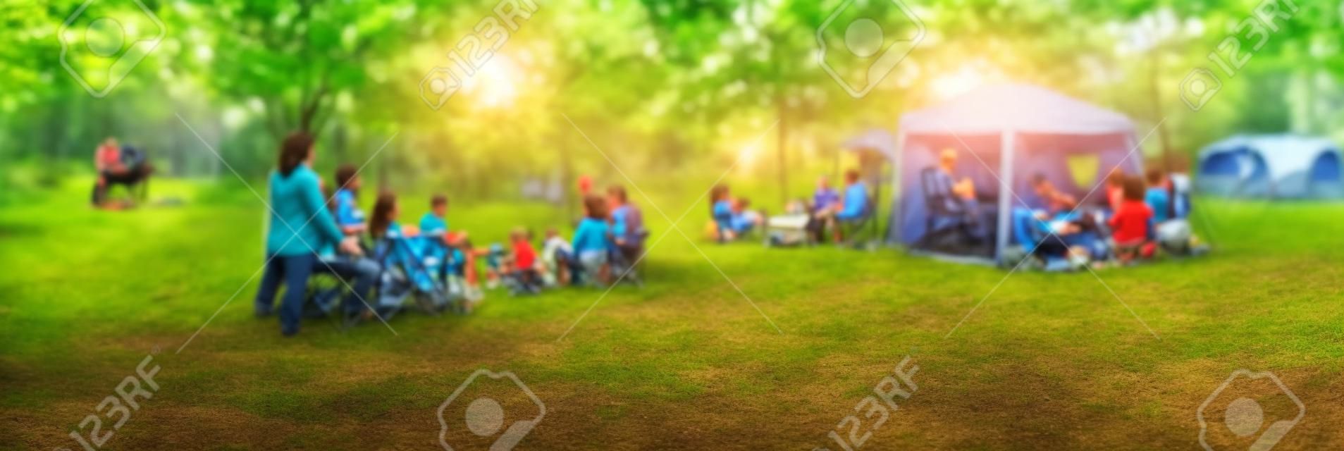 Panoramic view blurry background group of family members enjoy camping at local park