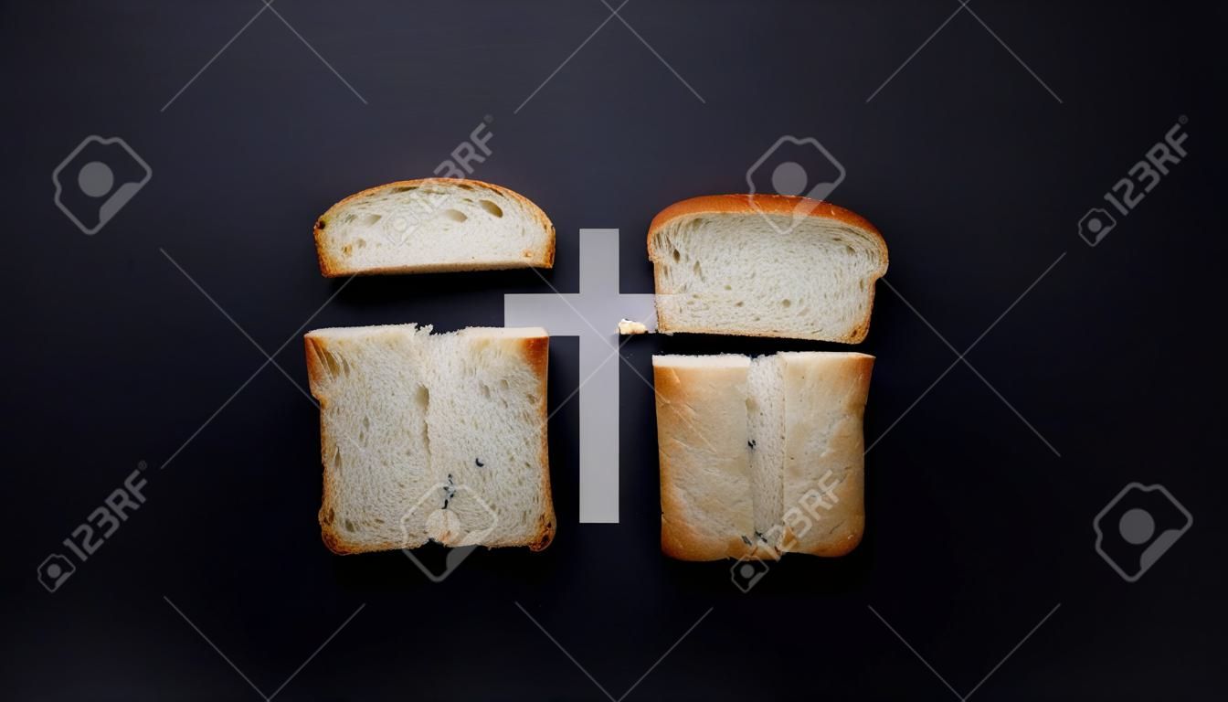 Nuestro pan de cada día, metáfora y signo. Cruz, valores cristianos, concepto de religión cristiana. Pan en forma de cruz sobre un fondo negro, vista superior con espacio de copia