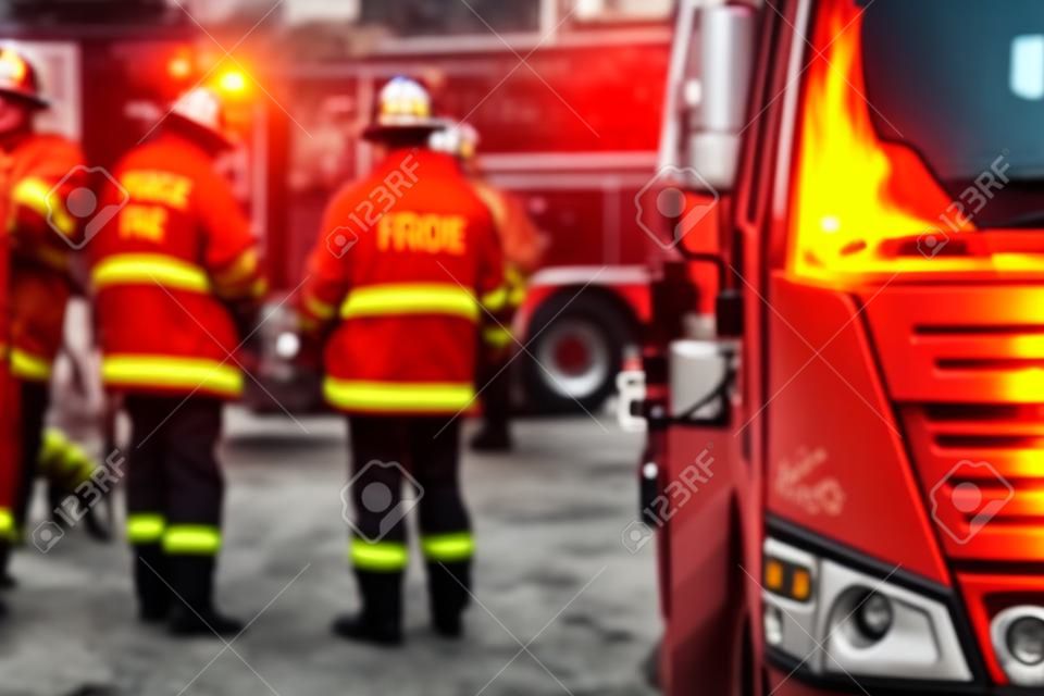 Groep brandweermannen in uniform tijdens brandbestrijding operatie in de straten van de stad, brandweerlieden met de brandweerwagen vrachtwagen vechtende voertuig op de achtergrond, nood