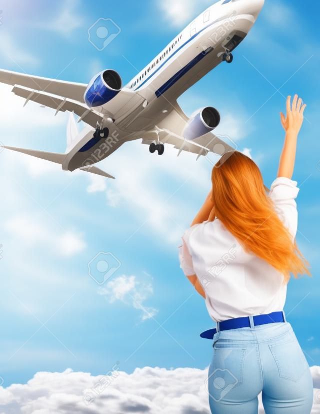 Girl and the airplane in flight, landscape with woman standing with hands raised up, waving arms and flying passenger airplane, female tourist and landing commercial aircraft, summer sunny day