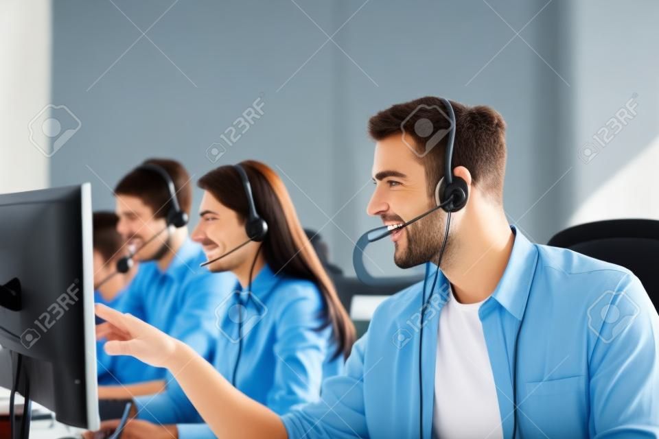 Portret van call center werknemer vergezeld door zijn team. Lachende customer support operator op het werk.