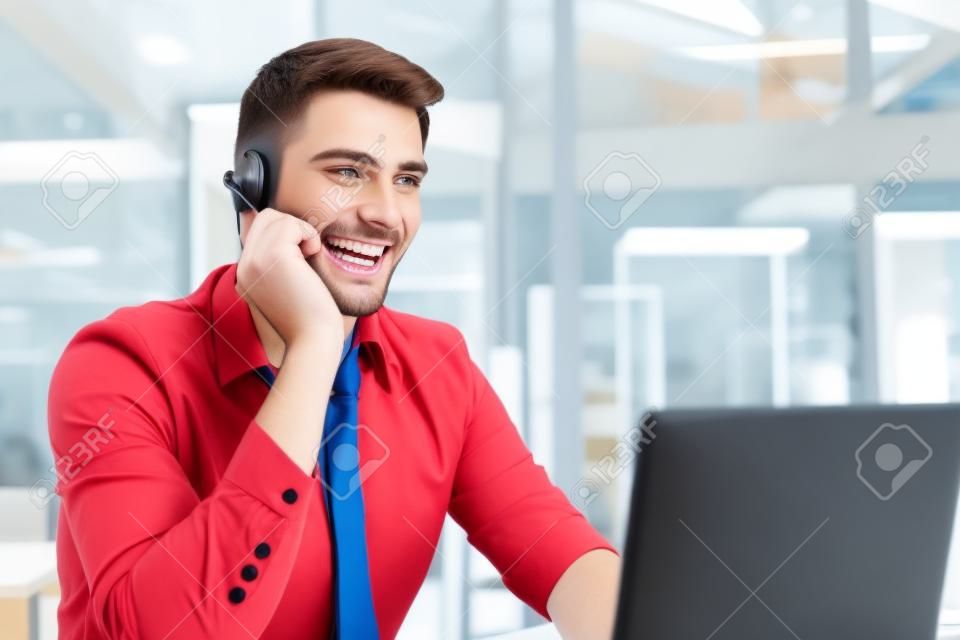 Szczęśliwy młody mężczyzna wykonawczy obsługi klienta pracujący w biurze
