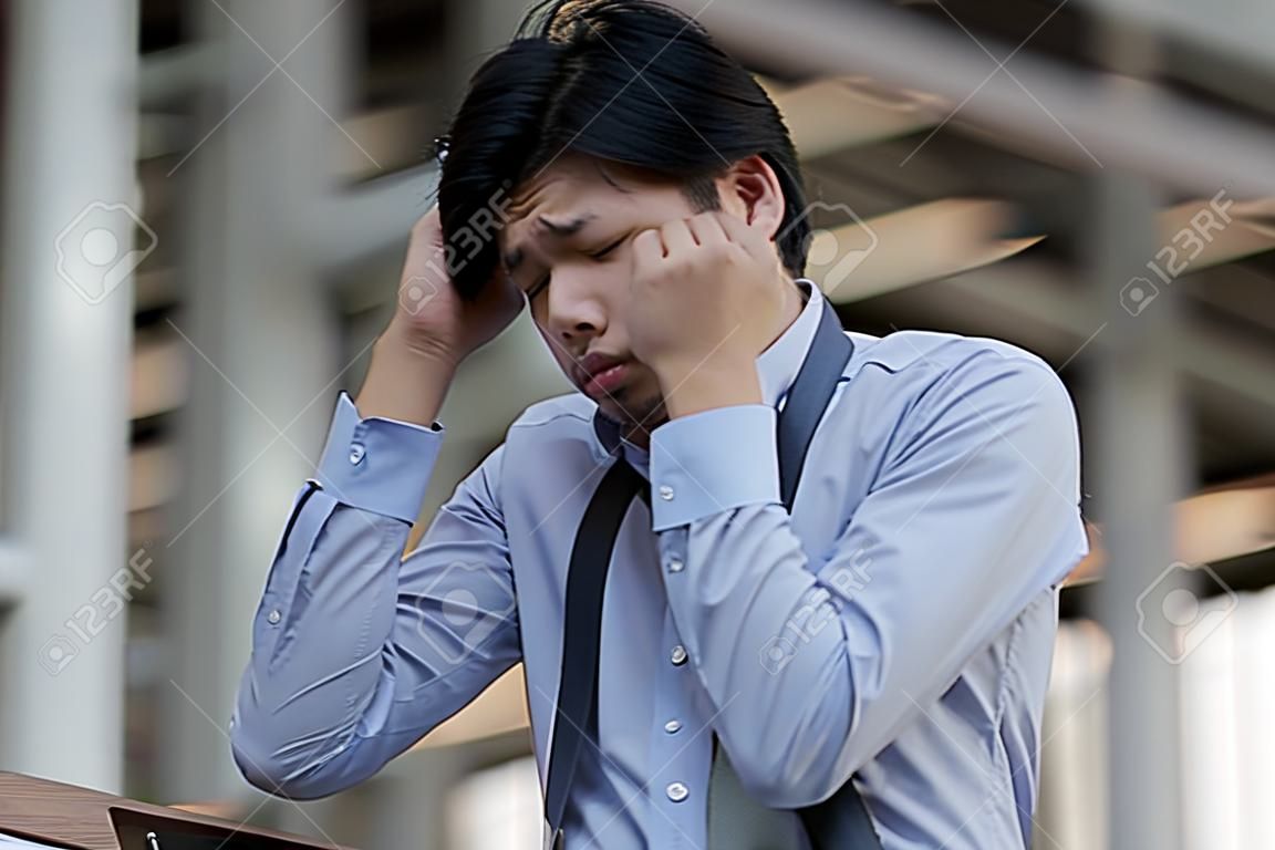 Stressed young Asian business man feeling tired and exhausted with his job
