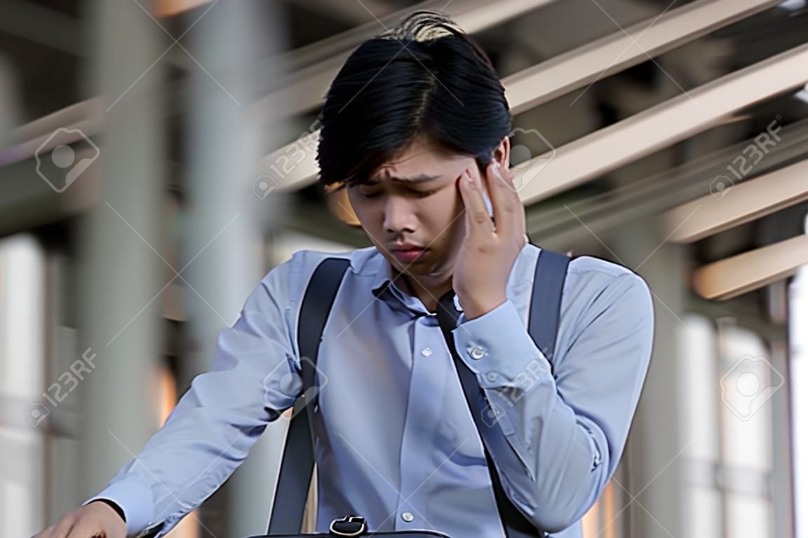 Stressed young Asian business man feeling tired and exhausted with his job
