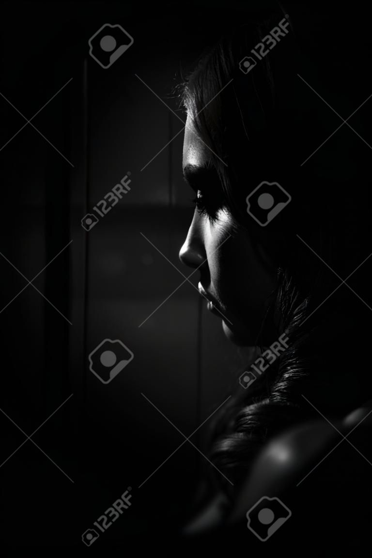 Elegant sad girl profile in the dark.
