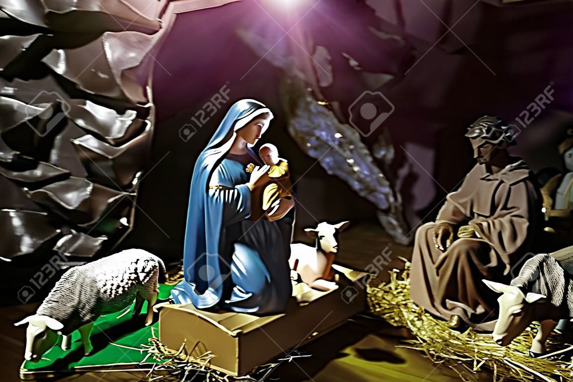 Dzieciątko Jezus leżące w żłóbku lub żłobie w boskim świetle. Figurki Maryi Panny, św. Józefa, owcy, osła, wołu w jaskini. Szopka. Święta Rodzina. Chrześcijaństwo, religia. Obchodzenie Bożego Narodzenia
