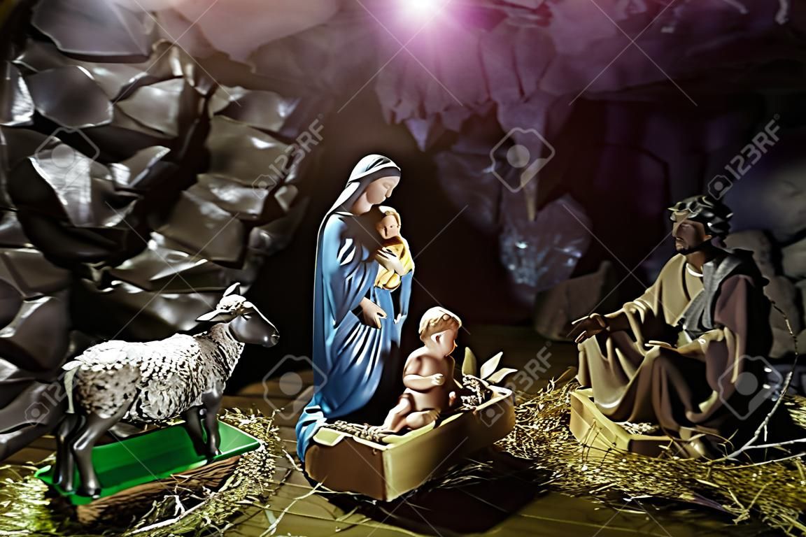 Dzieciątko Jezus leżące w żłóbku lub żłobie w boskim świetle. Figurki Maryi Panny, św. Józefa, owcy, osła, wołu w jaskini. Szopka. Święta Rodzina. Chrześcijaństwo, religia. Obchodzenie Bożego Narodzenia