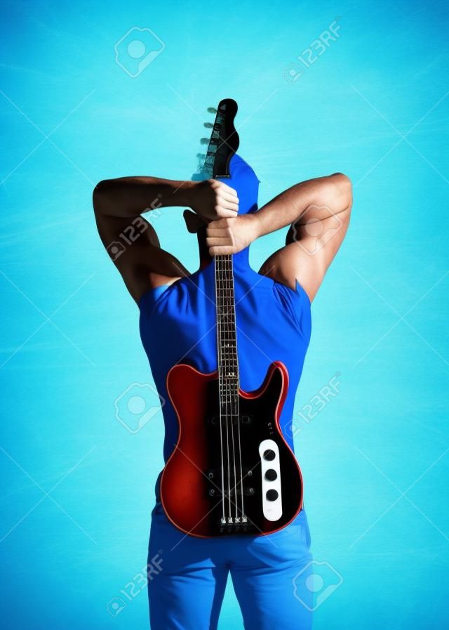 Sportsman with muscular back hold electric guitar on sunny blue sky. Music and sport concept