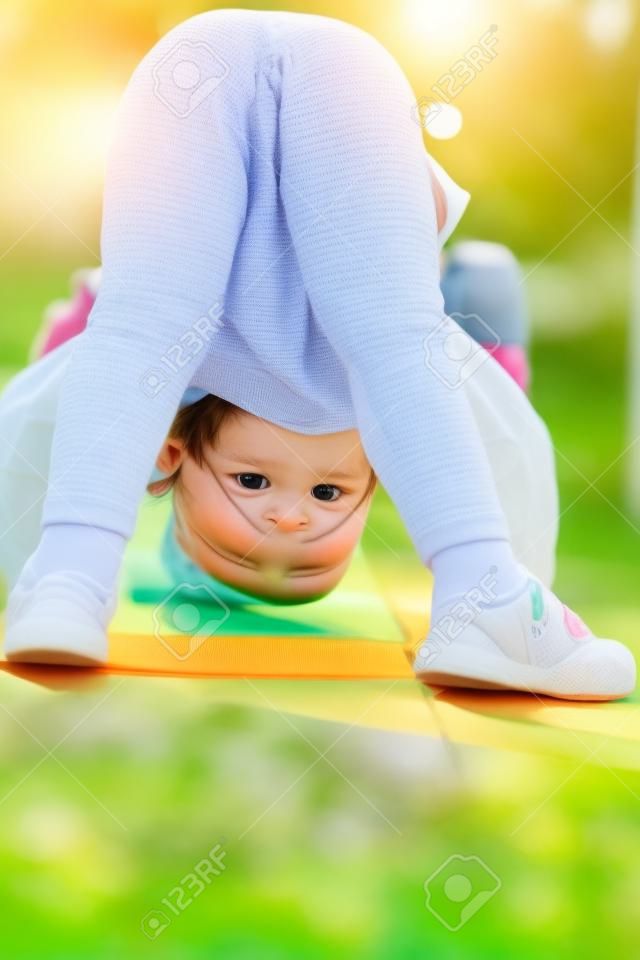 Kid girl stand on head on sunny day outdoor. Sport, yoga, pilates for child. Activity, energy concept. Childhood, playtime, lifestyle.