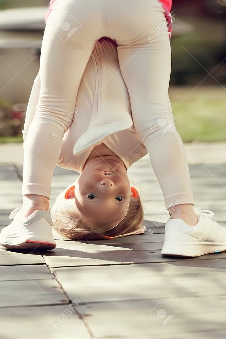 Kid fille debout sur la tête par une journée ensoleillée en plein air. Sport, yoga, pilates pour enfant. Activité, concept énergétique. Enfance, récréation, style de vie.