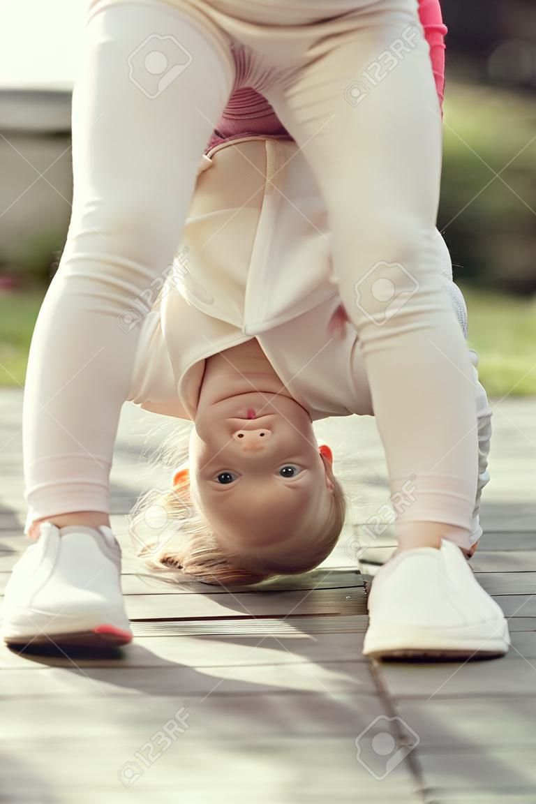 Kid fille debout sur la tête par une journée ensoleillée en plein air. Sport, yoga, pilates pour enfant. Activité, concept énergétique. Enfance, récréation, style de vie.