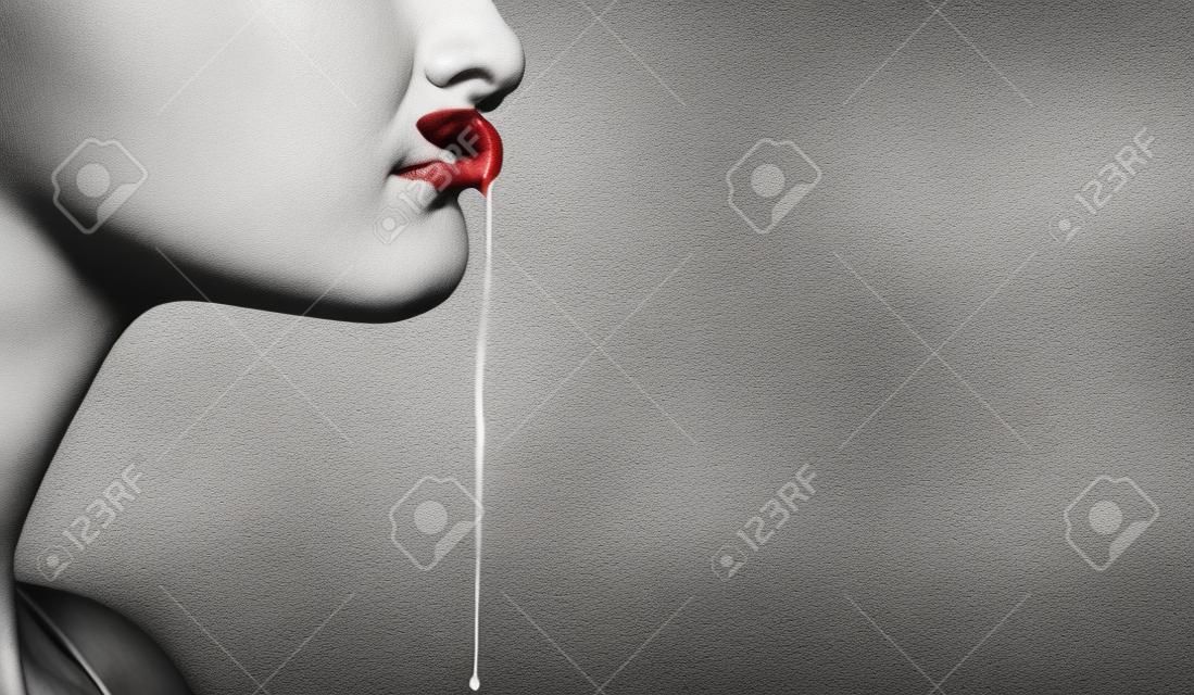 Part of female face with saliva drool from mouth lips on blurred white brick wall. Disorder, autism, madness, depression, disease concept, copy space