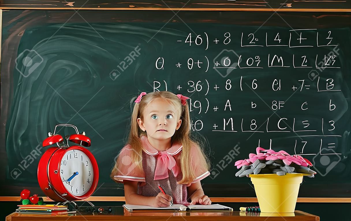 Adorable girl have lesson in drawing in primary school. Elementary school pupil draw on classroom chalkboard.
