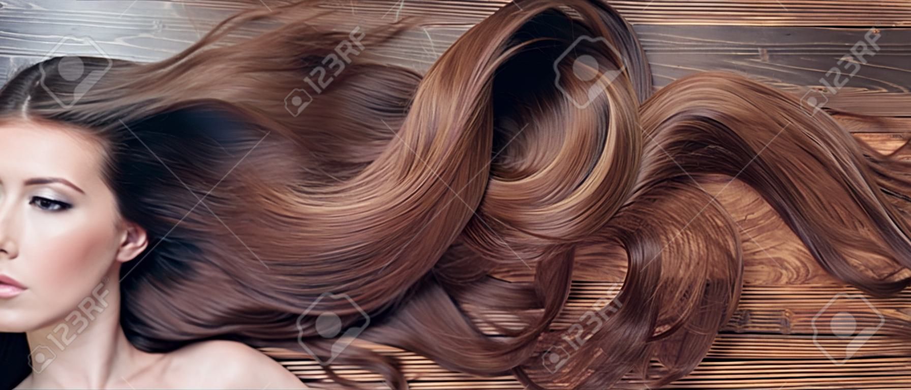 Mulher com cabelo longo bonito no fundo de madeira. Cabelo longo. Cortes de cabelo da moda. Salão de beleza do cabelo.