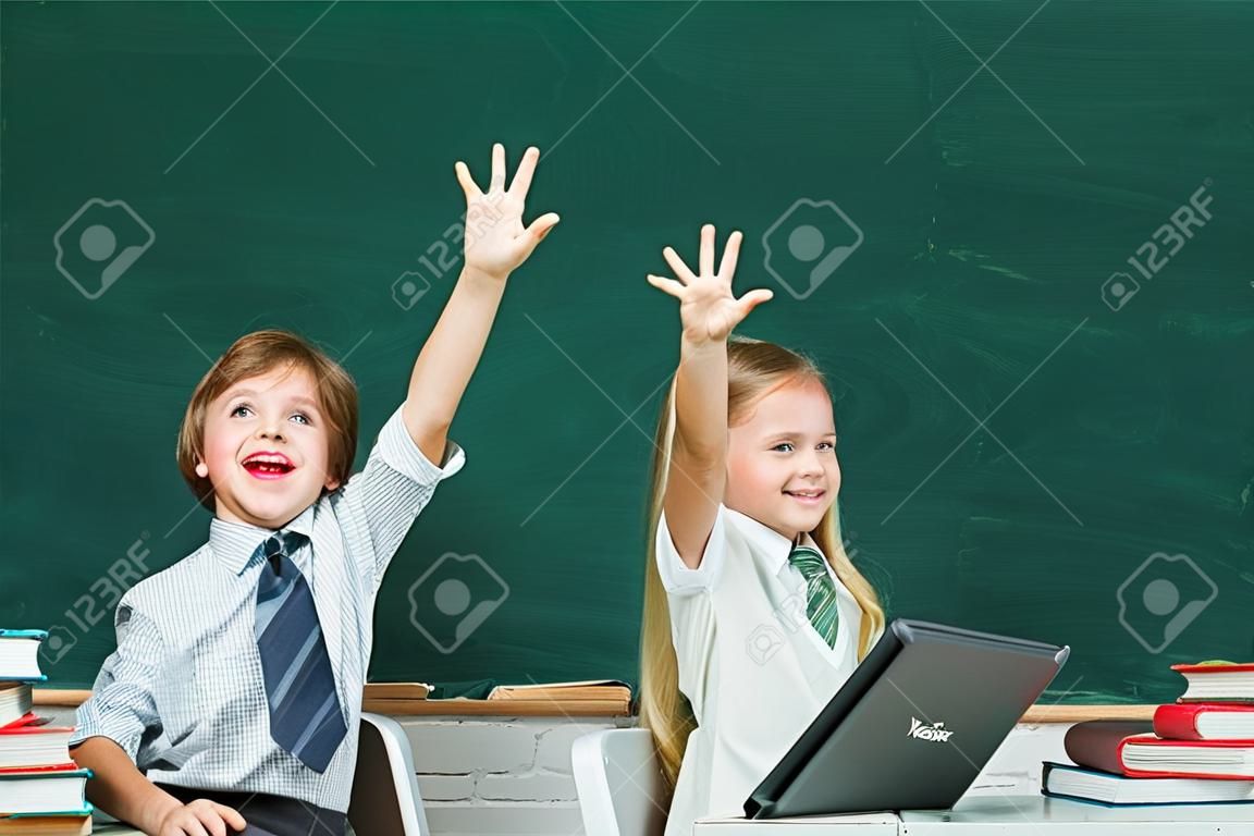 Kids gets ready for school. Couple of little girl and boy in classroom. Schoolgirl helping pupils studying at desks in classroom. Happy school kids. Apple and books - school concept.