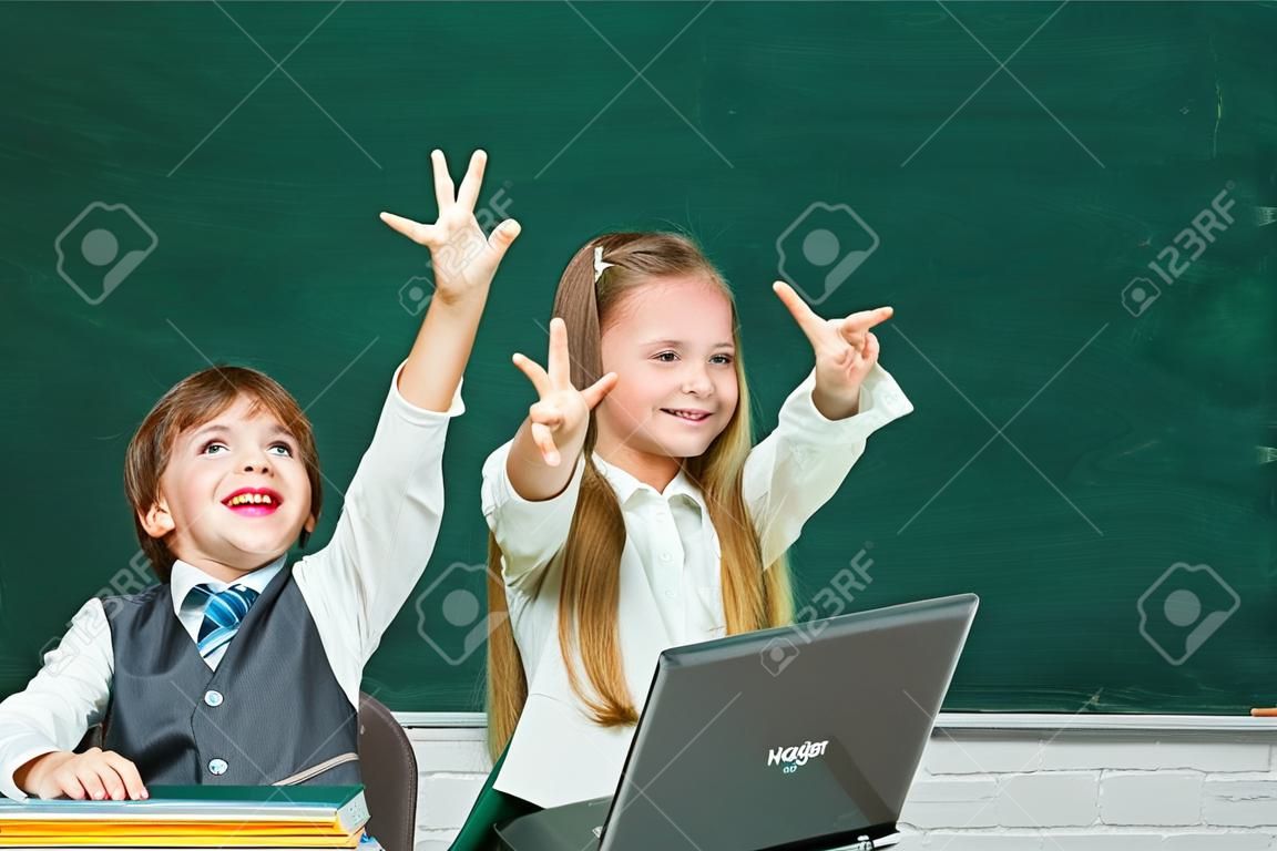 Kids gets ready for school. Couple of little girl and boy in classroom. Schoolgirl helping pupils studying at desks in classroom. Happy school kids. Apple and books - school concept.