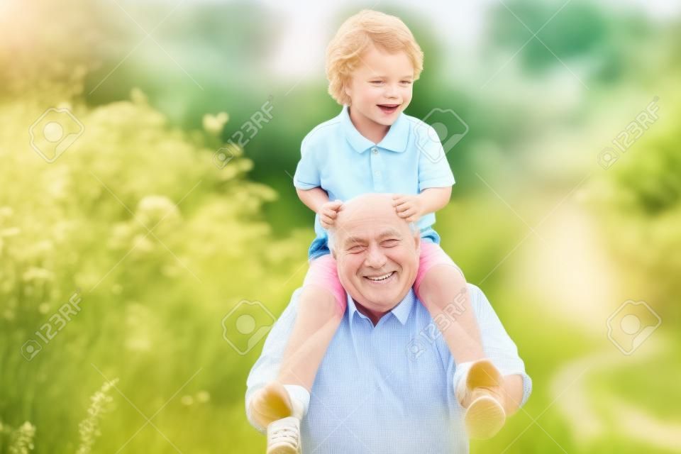 Gelukkige familie - grootvader en kind op weide in de zomer op de natuur. Gelukkige vreugdevolle grootvader hebben plezier kotsen in de lucht kleinzoon - familieconcept.