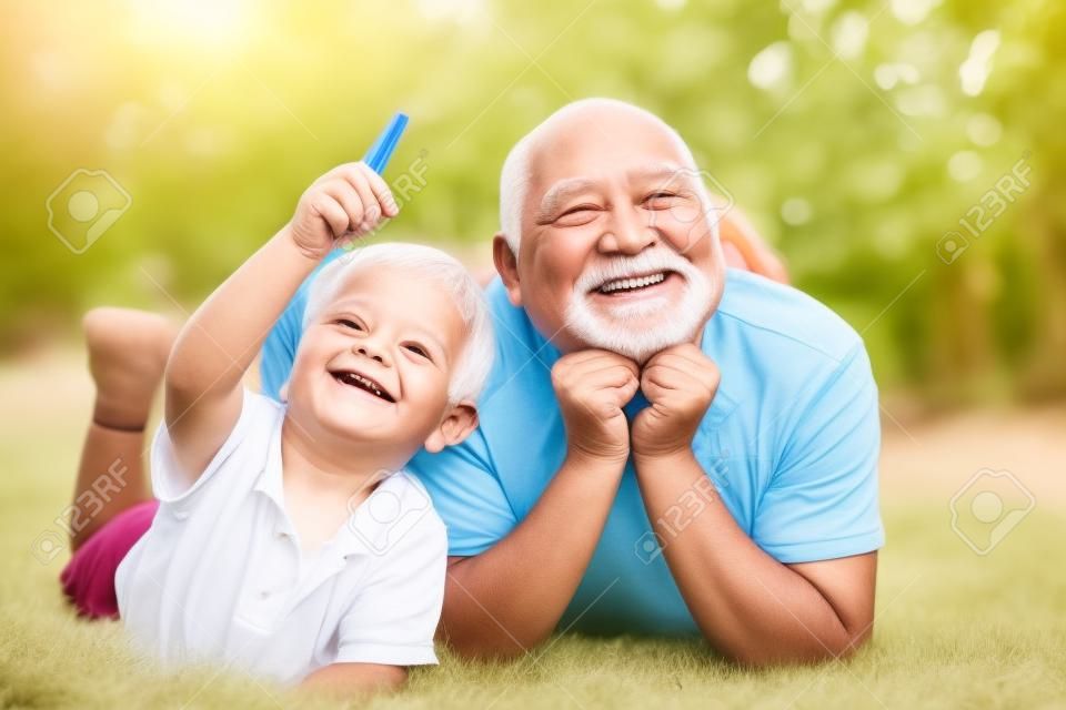 Szczęśliwy starszy człowiek Dziadek z wnukiem ładny mały chłopiec, grając i patrząc na kamery. Ładny chłopiec dziecko przytulanie dziadka.