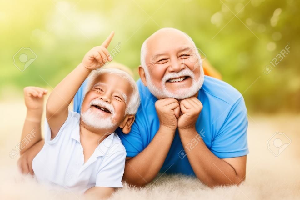 Szczęśliwy starszy człowiek Dziadek z wnukiem ładny mały chłopiec, grając i patrząc na kamery. Ładny chłopiec dziecko przytulanie dziadka.