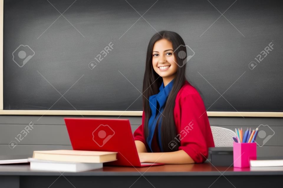 Successful female student at classroom of university. Portrait of young female college student studying in classroom on class with blackboard background.