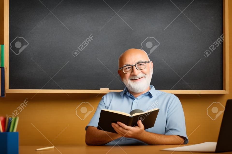 Hombre maestro maduro. retrato de feliz tutor senior en gafas con libro en la pizarra en clase en la escuela secundaria o collage. antiguo estudiante de estudio en la universidad.