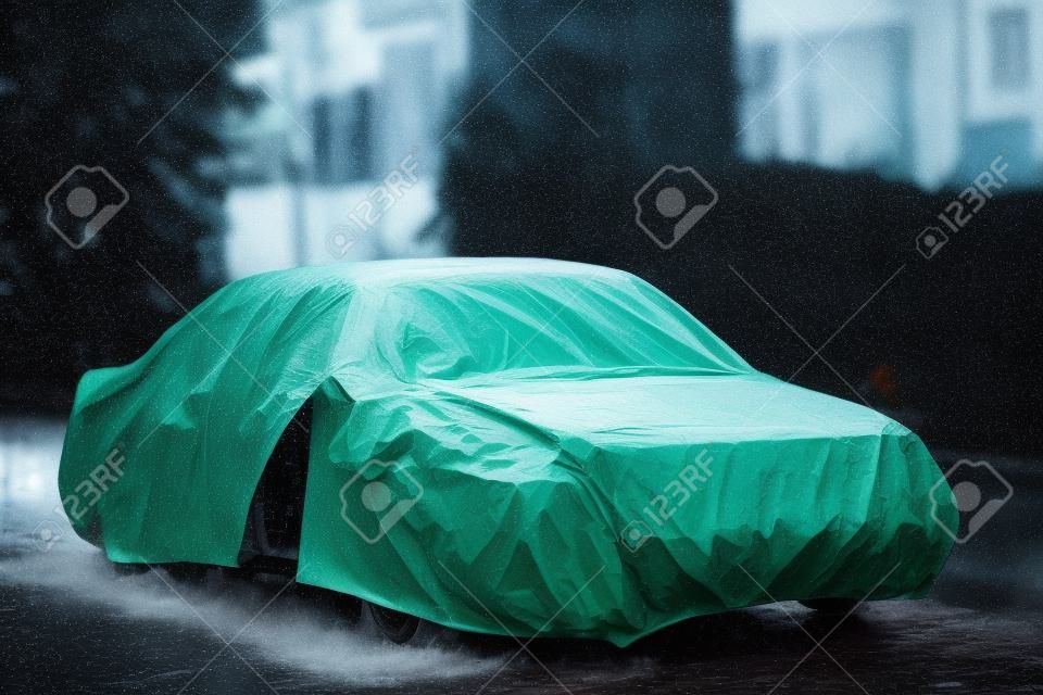 A parked car with protective cover in wet weather 